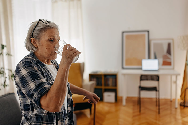 En äldre kvinna dricker vatten